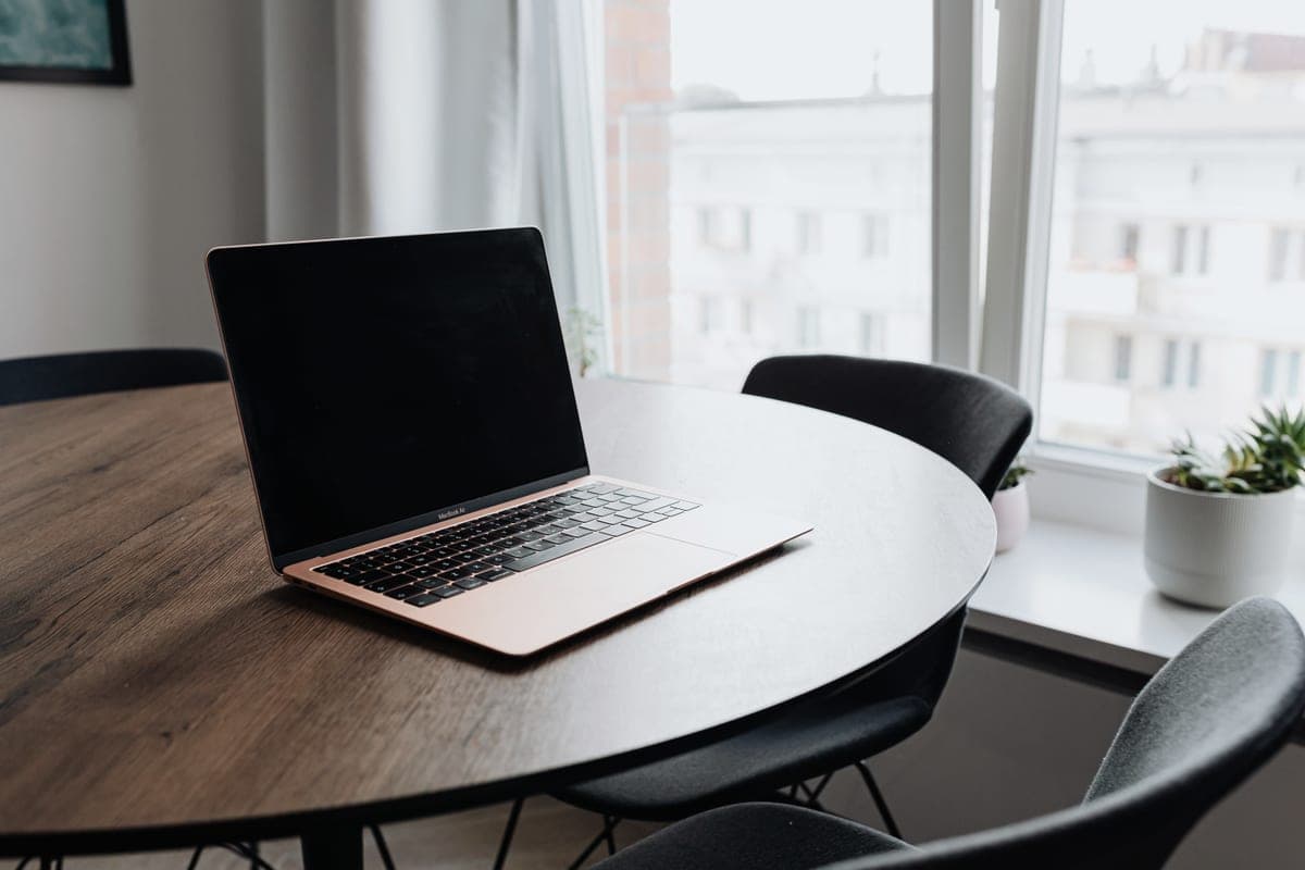 A compact home office desk against an apartment wall with a laptop and chair