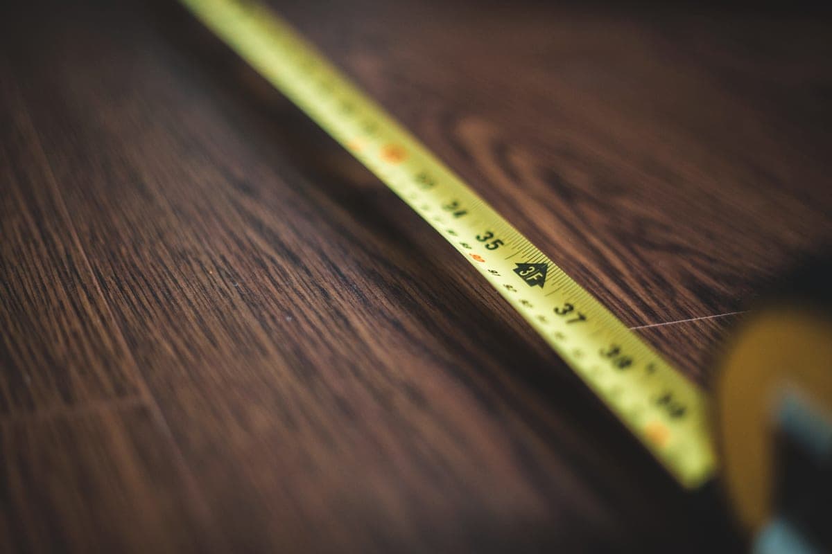 A retractable tape measure extended across a wooden floor