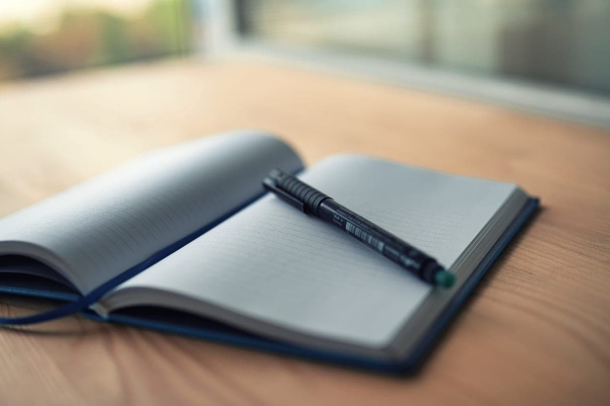 An open notebook and pen on a desk with handwritten measurements