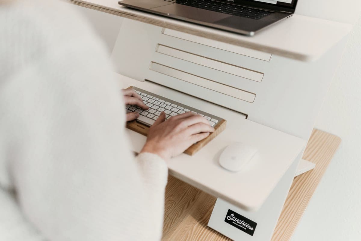 A height-adjustable standing desk in a small room with a laptop at standing height