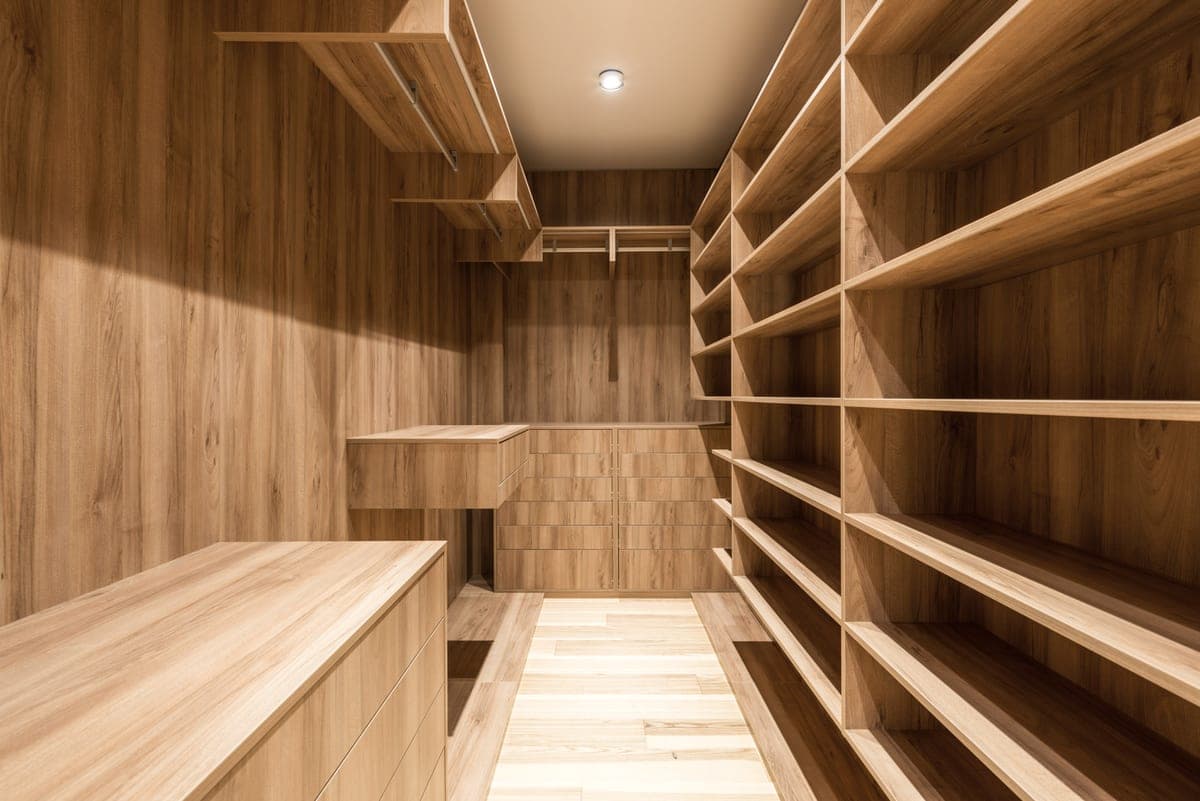 A narrow apartment closet with folded items stacked against the wall